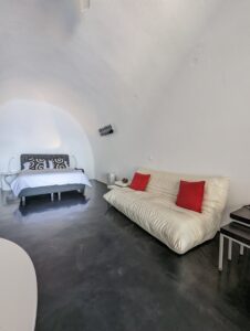 Minimalist Room with Red Accents Minimalist room with white curved ceiling, bed, sofa with red cushions, and dark flooring.