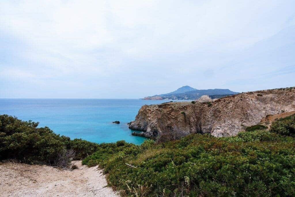 Rocky coastal cliffs with distant mountain and green shrubbery Rocky coastal cliffs with green shrubbery overlooking the blue sea and distant mountains.