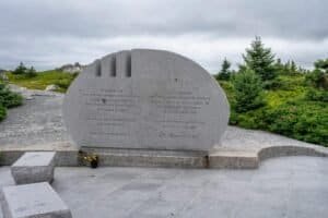 Stone memorial with bilingual inscription honoring 229 victims of Swissair Flight 111, outdoors with greenery.