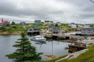 Coastal village with colorful houses, wooden fishing shacks, boats, docks, and green hills under clouds