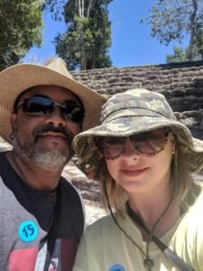 Two people wearing hats and sunglasses with number 15 stickers on their clothing outdoors.